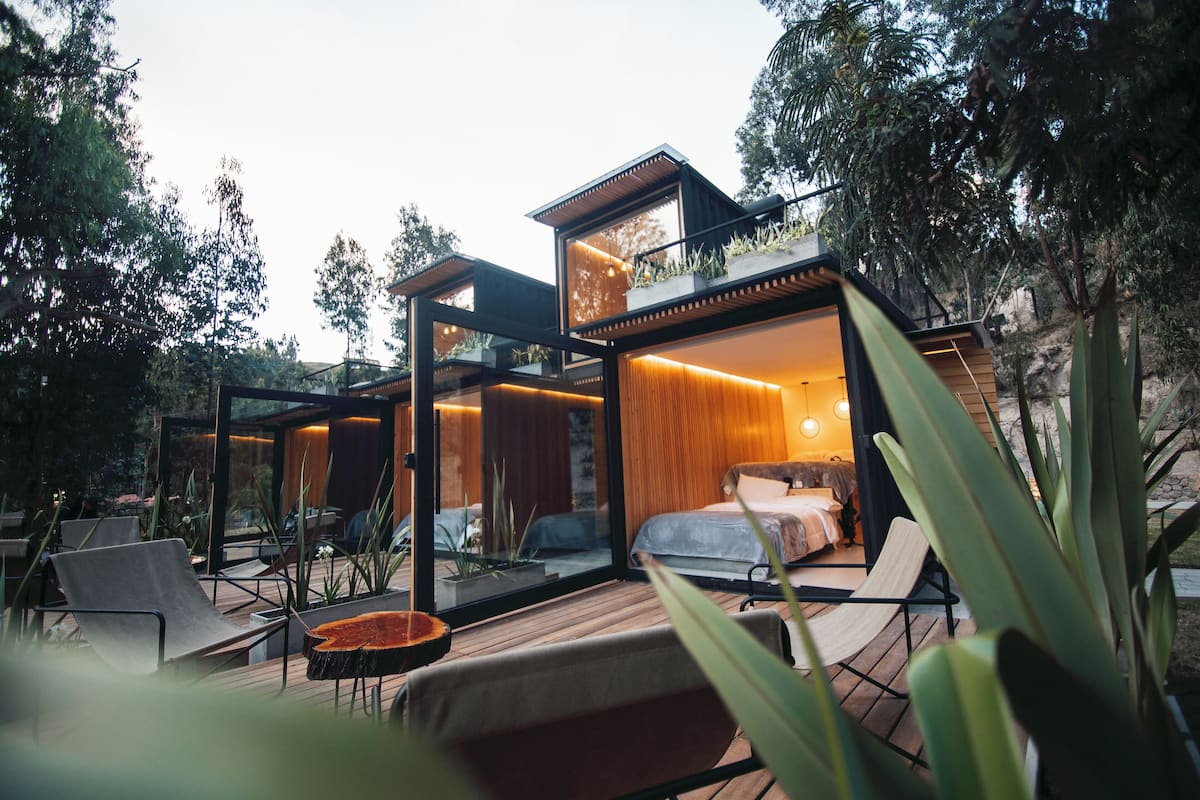 Un espacio exterior moderno con terraza de madera, sillas de descanso y una mesa de comedor.