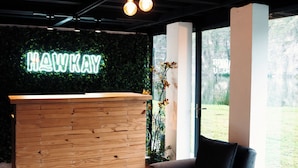 A reception area with a wooden desk, a neon sign, and a view of the outdoors. - Hawkay Glamping (Panzaleo)