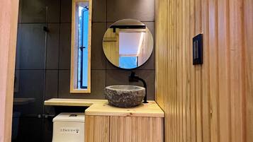 Un baño moderno con un lavabo de piedra, tocador de madera y un inodoro.