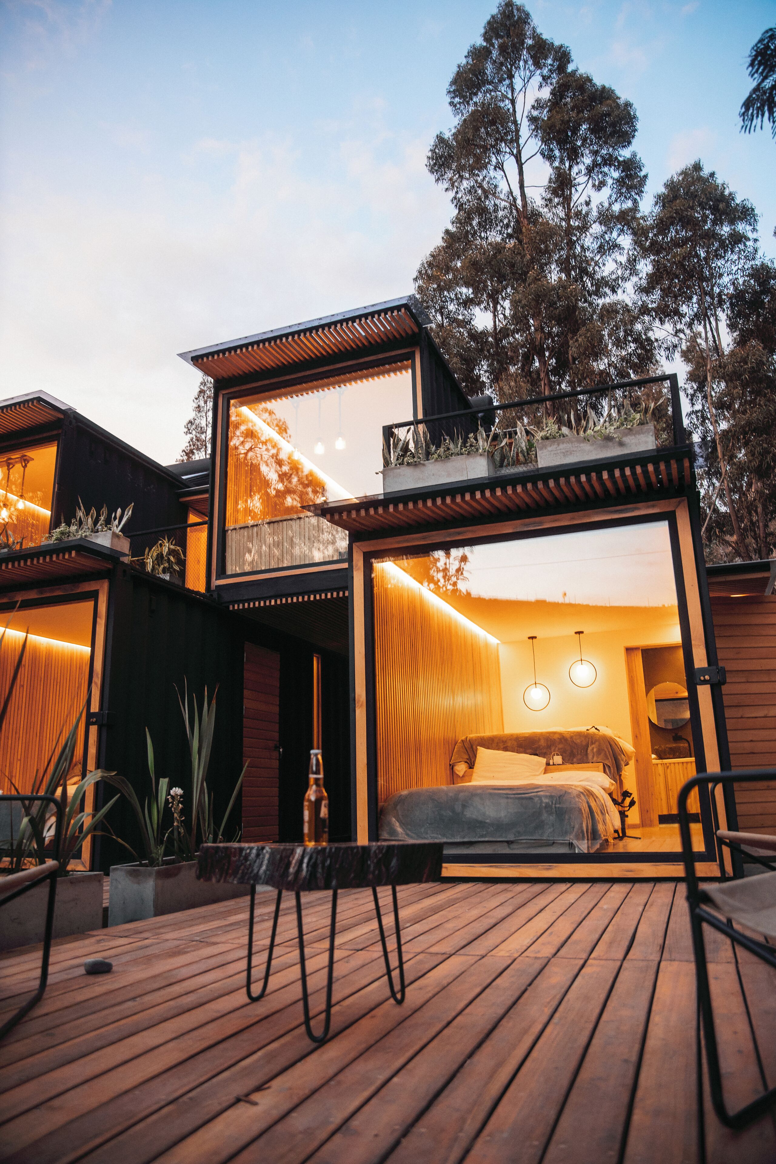 A modern two-story house with a wooden deck, large windows, and a balcony.