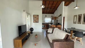Un salon moderne comprenant un canapé, une table basse, un téléviseur et un coin repas avec une table et des chaises.
