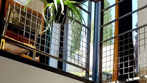 A room with a large window, a potted plant, and a wooden bench. - Gîte de La Pyranvôle (Lacrost)