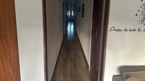 Un pasillo con suelo de madera, paredes blancas y una puerta a la derecha.