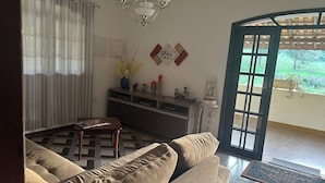 Una sala de estar con sofá, una mesita de centro, un aparador con adornos y vistas al exterior a través de una puerta.