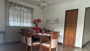 Un comedor con una mesa de madera, seis sillas, un florero y un adhesivo en la pared.