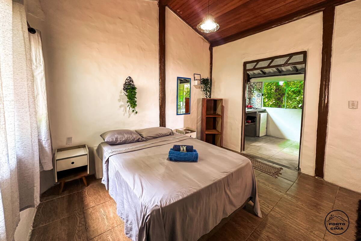 Une chambre à coucher avec un lit, une table de chevet, un miroir, une étagère et une vue sur l  ’extérieur.