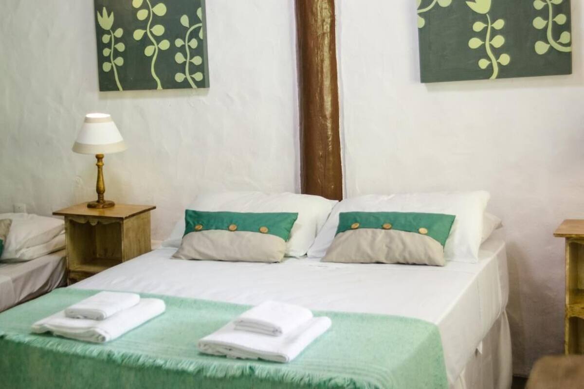 Une chambre d’hôtel avec deux lits, une table de chevet avec une lampe et des motifs floraux verts sur le mur.