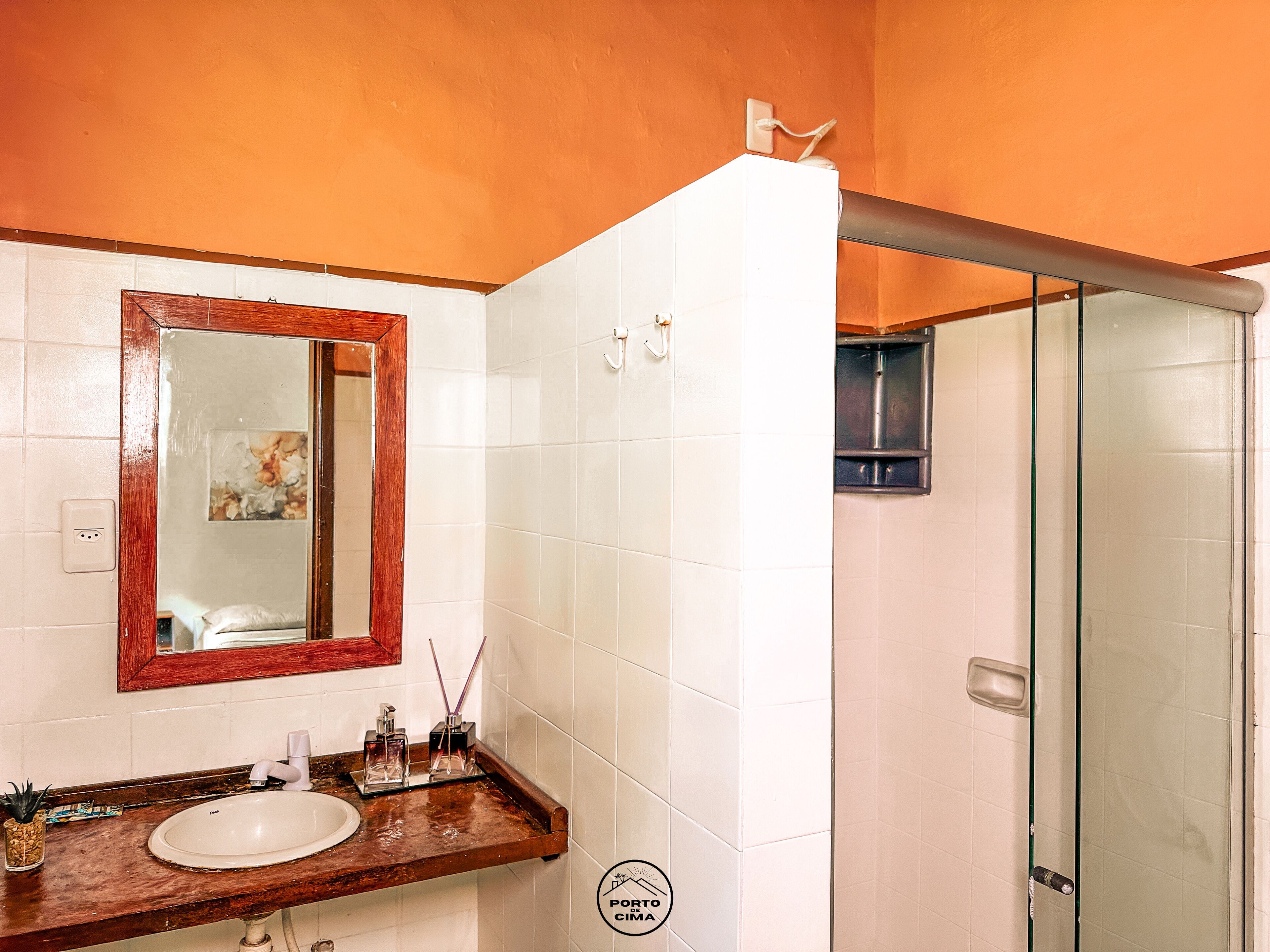 Een badkamer met een wit wastafelmeubel, spiegel en douche.