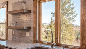 A kitchen with a stone backsplash, a stainless steel sink, and wooden window frames. - Bethel Escape:Sleeps 10,Hot Tub,GameRoom,Fire Pit (Bethel)