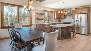 A spacious kitchen with a large island, wooden cabinets, and a stainless steel refrigerator. - Bethel Escape:Sleeps 10,Hot Tub,GameRoom,Fire Pit (Bethel)