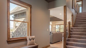A staircase leading to a second floor, a bench with a pillow, and a view of a living room with a couch. - Bethel Escape:Sleeps 10,Hot Tub,GameRoom,Fire Pit (Bethel)