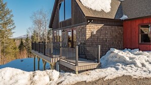 A two-story wooden cabin with a deck, surrounded by snow. - Bethel Escape:Sleeps 10,Hot Tub,GameRoom,Fire Pit (Bethel)