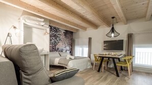 Une pièce confortable avec un lit, un canapé, une table à manger avec des chaises, un téléviseur et une grande fenêtre.