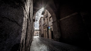 Une ruelle étroite aux murs de pierre, baignée par le soleil qui filtre à travers une arche.