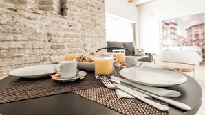 Une table mise pour le petit-déjeuner, avec des assiettes, des tasses et un verre de jus d’orange.