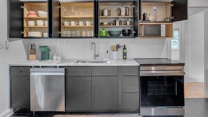 A modern kitchen with open cabinets, a dishwasher, a microwave, and an oven.