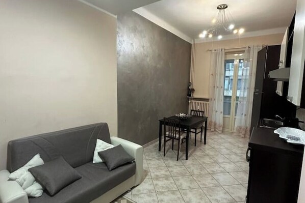 A living room with a sofa and a dining table with chairs.