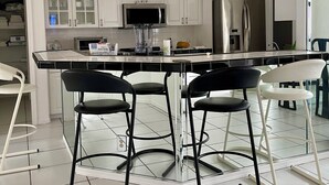 A modern kitchen with white cabinets, a stainless steel refrigerator, a microwave, and a bar area with stools. - Charming 3-bedroom villa with AC and WiFi in lovely Sebastian (Sebastian)