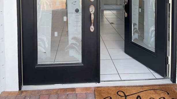 A black-framed door with a glass panel reflecting a palm tree and a bird. - Charming 3-bedroom villa with AC and WiFi in lovely Sebastian (Sebastian)