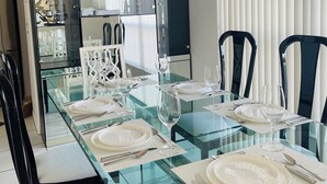 A dining area with a glass table set for four, black chairs, and a hanging light fixture. - Charming 3-bedroom villa with AC and WiFi in lovely Sebastian (Sebastian)