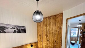 A bedroom with a wooden headboard, a large bed with two pillows, a hanging light fixture, and a painting on the wall.