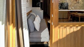 A cozy room with a checkered sofa, a wooden door, and a view of a dining area.