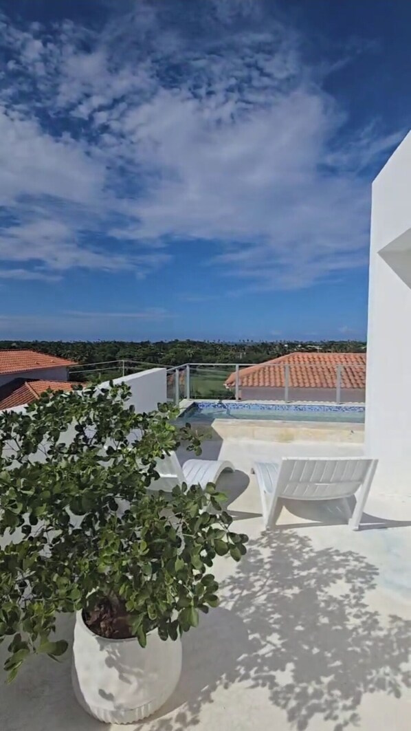 Relax on the outdoor terrace with a view of the surrounding landscape, featuring a potted plant and comfortable lounge chairs.