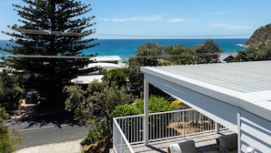 A modern house with a balcony overlooking a coastal view.