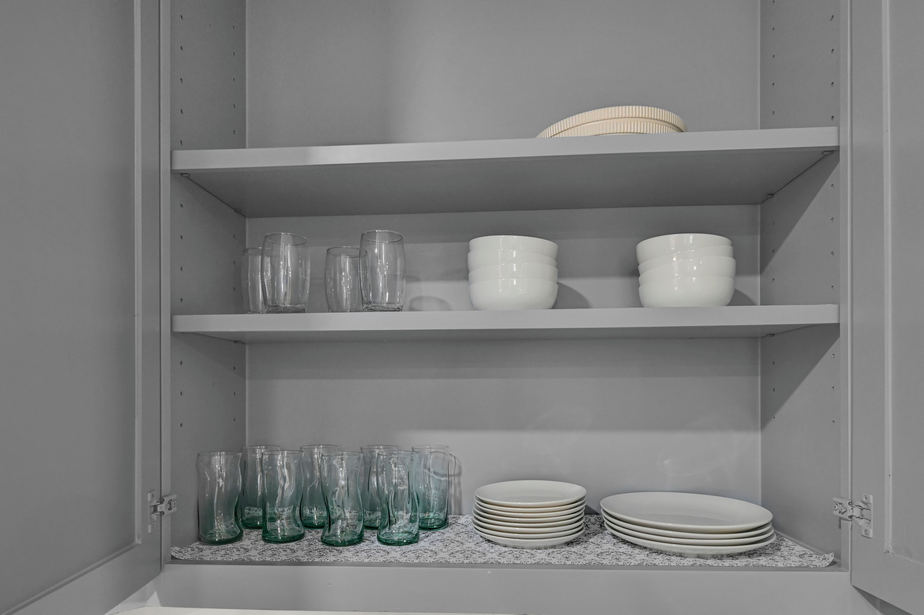 A cabinet with shelves containing glassware and plates.