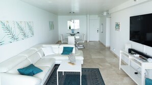 Een moderne woonkamer met een witte bank, een salontafel en een tv op een standaard.