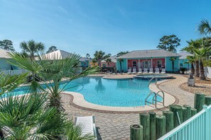 Relax by the resort pool surrounded by lounge chairs and palm trees.