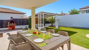 Een terras met een eettafel voor vier personen, omringd door rieten stoelen.