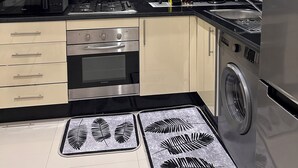 Een moderne keuken met een fornuis, oven, magnetron en wasmachine.