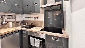 Une cuisine moderne avec des meubles de couleur sombre, une hotte en acier inoxydable, un four encastré et un évier.