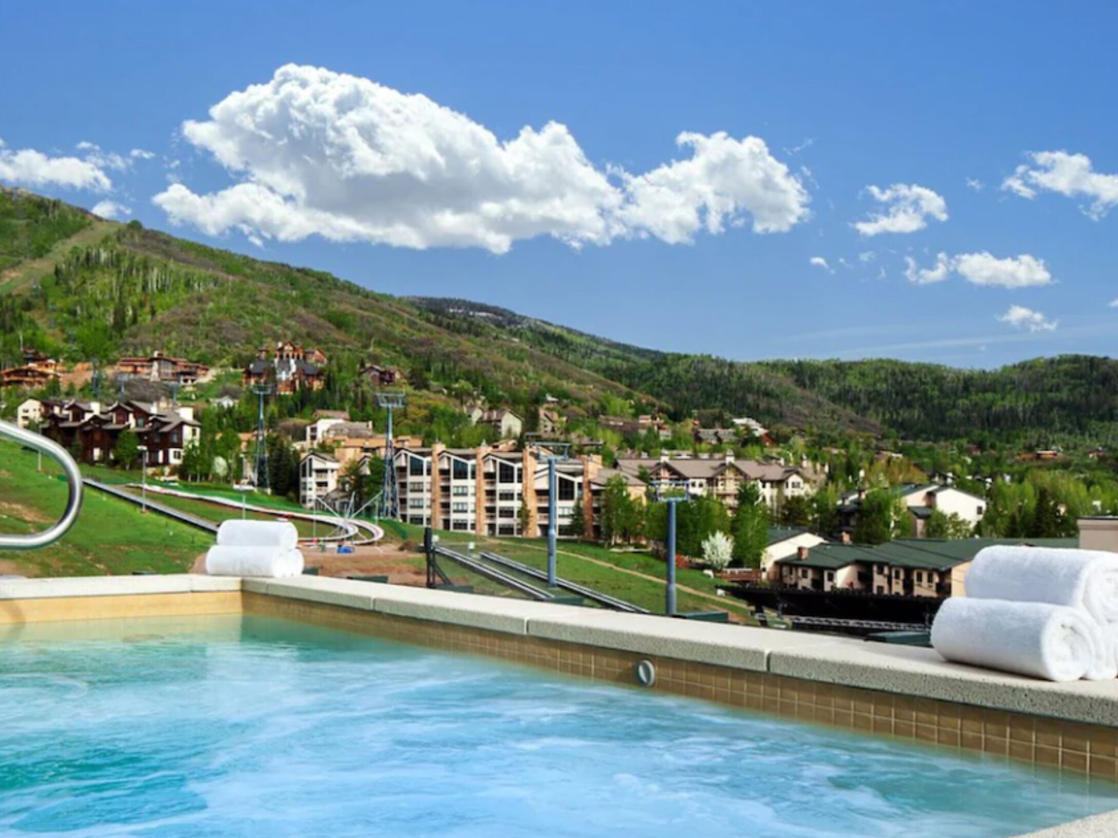 A swimming pool with a view of a mountainous area and residential buildings.