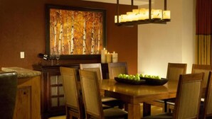 Un coin repas avec une table en bois, des chaises et un tableau accroché au mur.