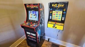 Dos máquinas de videojuegos, una con la etiqueta 'Midway Mortal Kombat' y la otra 'Pac-Man'.