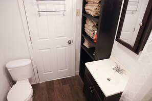Een badkamer met een wit toilet, een witte wastafel en een handdoekhouder.