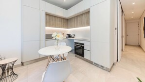 A modern kitchen with white cabinetry, a built-in oven, and a dining area with a round table and chairs.