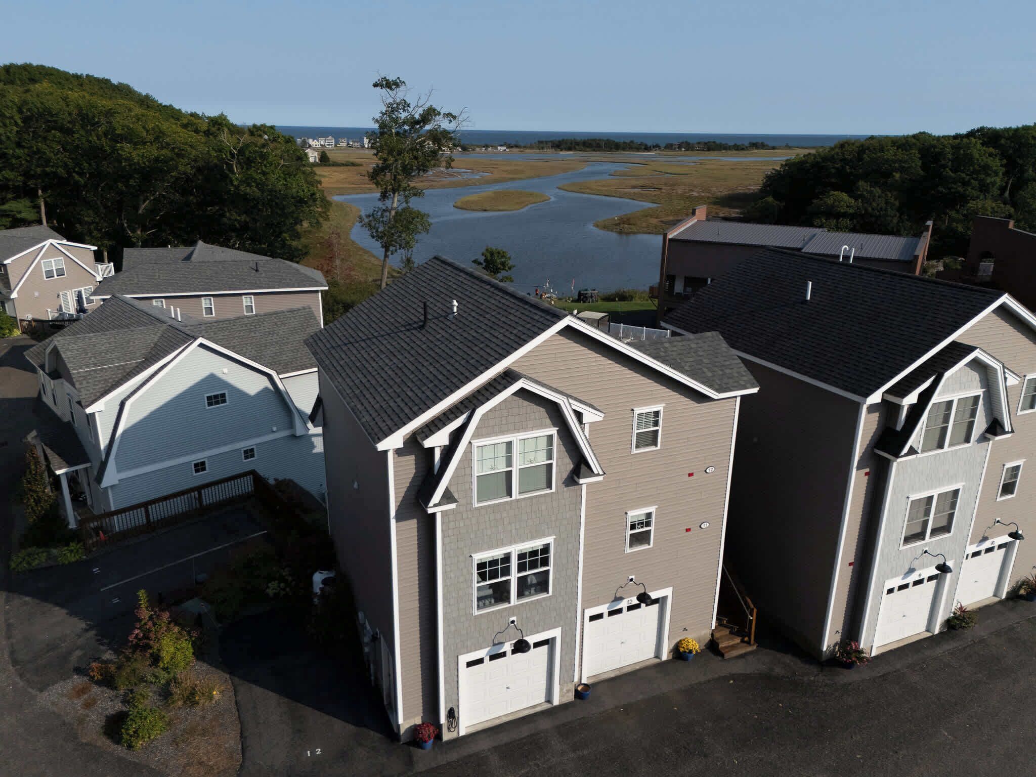 A residential area with multiple houses, a large body of water, and a clear sky.