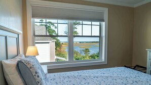 A bedroom with a large window offering a view of a river and greenery. - Ogunquit River Outlook (Wells)