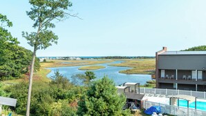 A view of a lakeside property with a pool, outdoor seating, and a building with multiple balconies. - Ogunquit River Outlook (Wells)