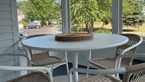 Eine überdachte Terrasse mit einem runden weißen Tisch und Korbstühlen.