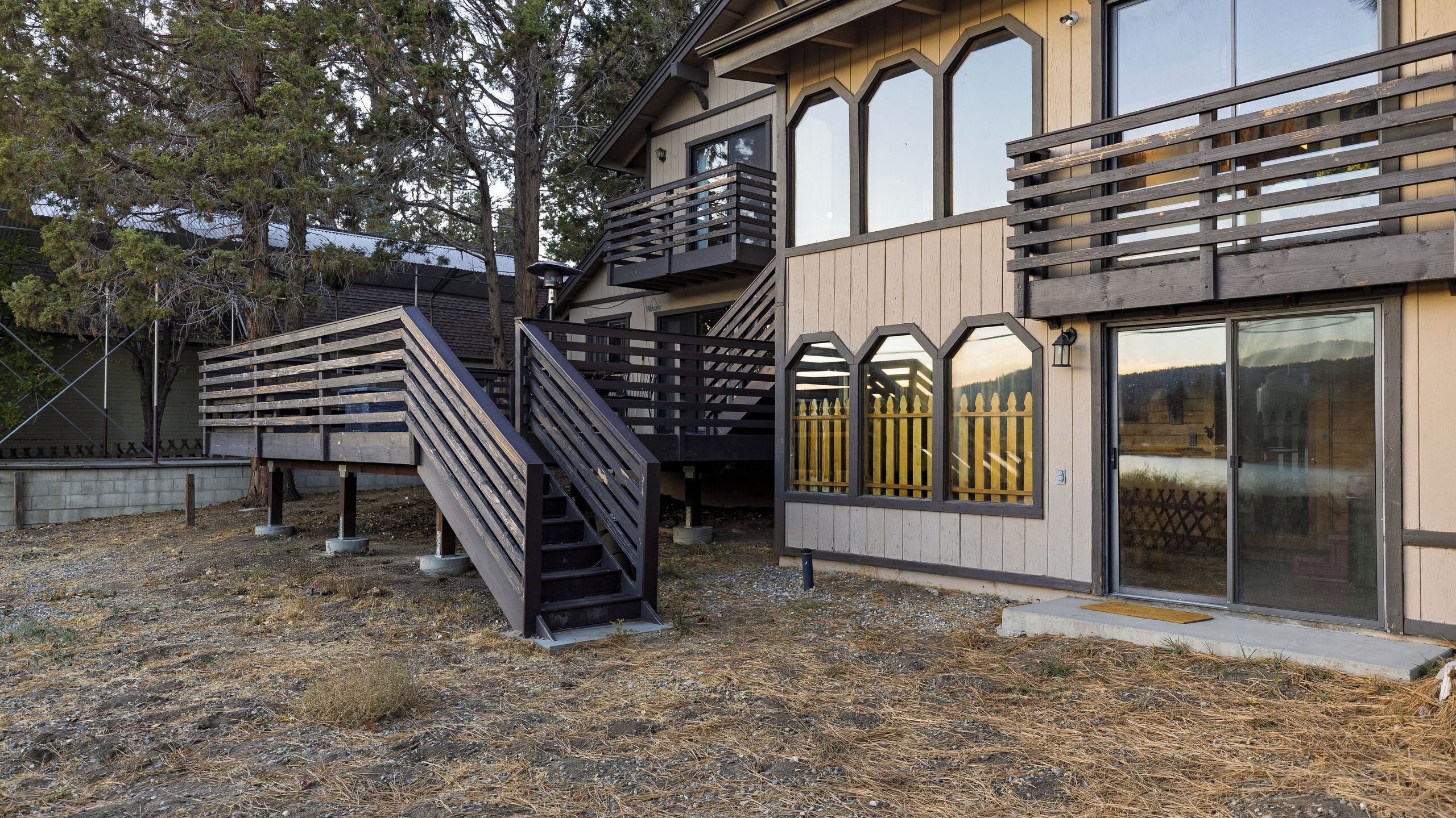 Un bâtiment moderne doté d’un escalier en bois, d’un balcon et de grandes fenêtres.