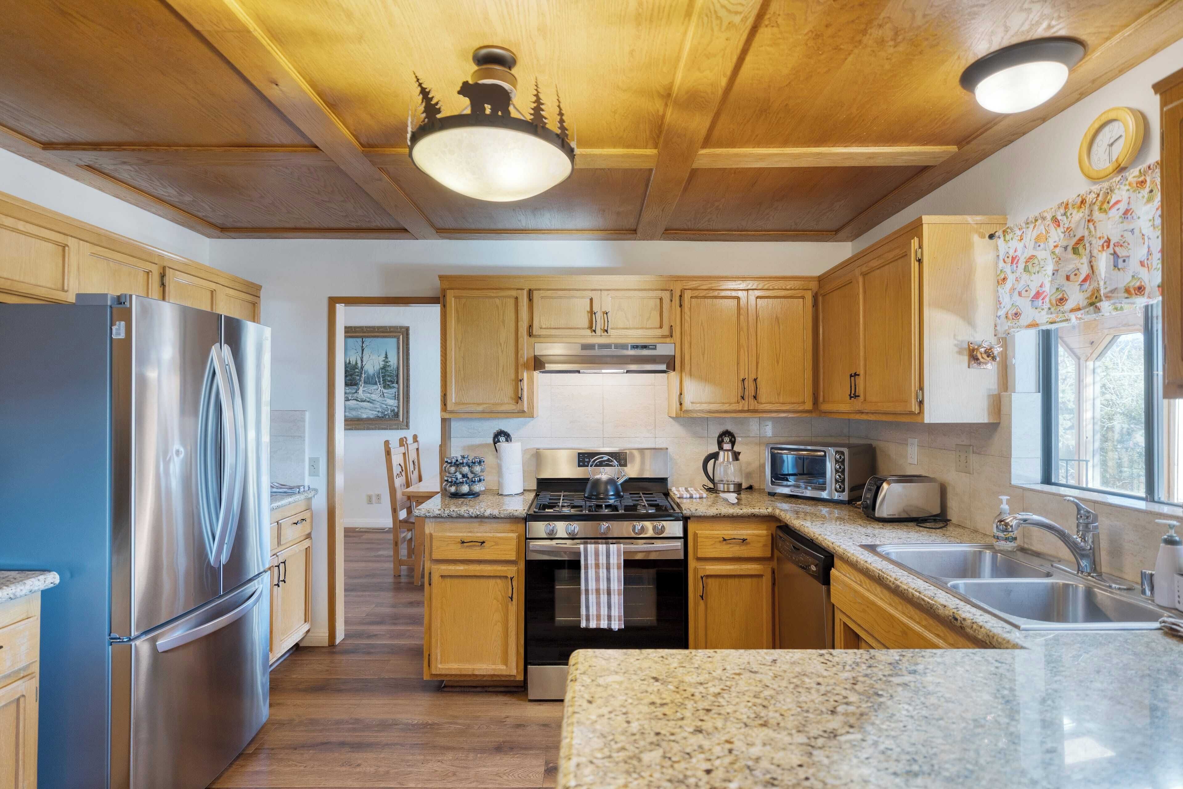 A kitchen with wooden cabinets, stainless steel appliances, granite countertops, and a wooden ceiling.