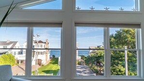 A room with large windows overlooking a residential area and a body of water.