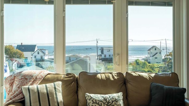 Een woonkamer met een groot raam met uitzicht op de kust.