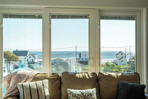 A living room with a large window overlooking a coastal view. - Family Tides (York)
