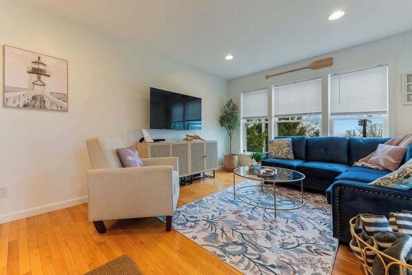 Un salon moderne avec un canapé, un fauteuil et un téléviseur à écran plat fixé au mur.