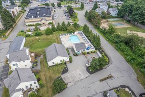 Vue aérienne d’un quartier résidentiel avec des maisons, une piscine et un court de tennis.